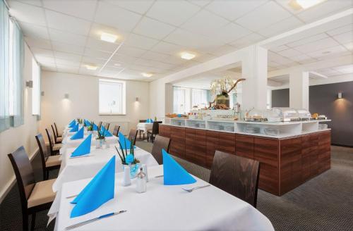 a dining room with tables and chairs with blue napkins at Hotel City Oase Lb in Ludwigsburg