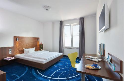 a hotel room with a bed and a desk and a table at Hotel City Oase Lb in Ludwigsburg