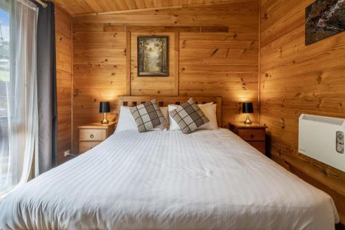 a bedroom with a bed with wooden walls and a window at Mole Creek Cabins in Mole Creek