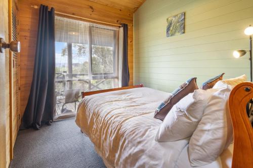a bedroom with a bed and a window in a room at Mole Creek Cabins in Mole Creek