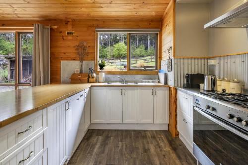 a kitchen with white cabinets and wooden walls at Mole Creek Cabins in Mole Creek
