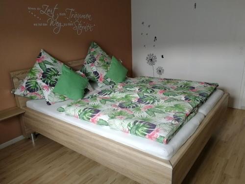 - un lit avec des couvertures et des oreillers verts et roses dans l'établissement Ferienwohnung Huschle, à Kappelrodeck