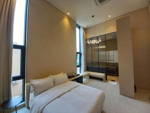 a bedroom with a large white bed and a large window at Hotel Libre in Siheung