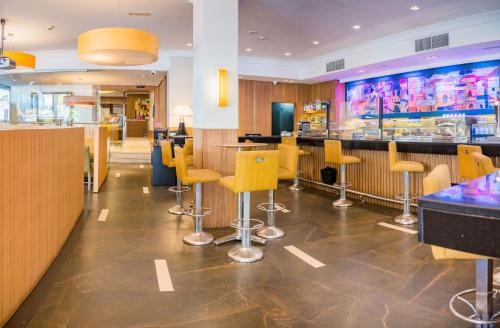 a restaurant with yellow chairs and a bar at Hotel Opera in Madrid
