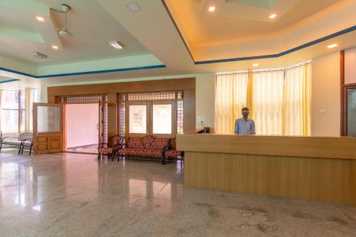 a man standing at a counter in a lobby at KSTDC Hotel Mayura Krishna Almatti in Bāgalkot