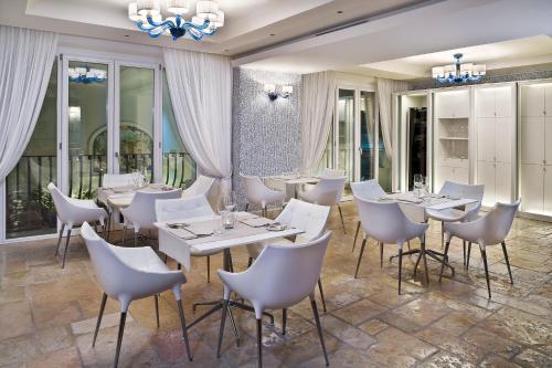 a restaurant with white tables and chairs and a chandelier at Hotel Villa Blu Capri in Anacapri