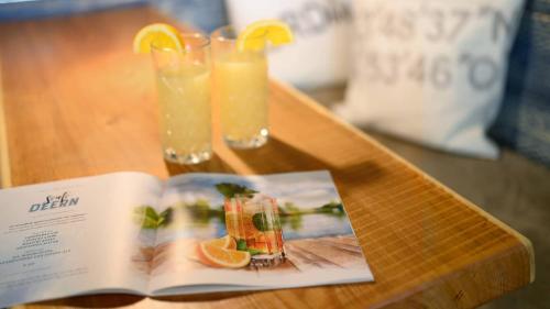 an open book on a table with two glasses of orange juice at Hotel Am Medemufer in Otterndorf