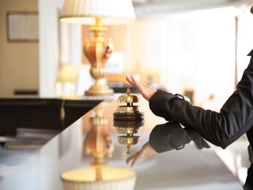 a person is reaching for a bell on a counter at Perugia Plaza Hotel in Perugia