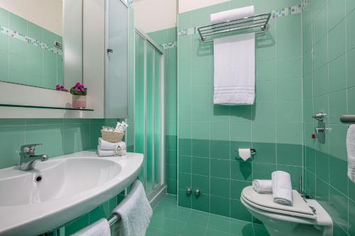 a green bathroom with a sink and a toilet at Hotel Medusa Splendid in Lignano Sabbiadoro