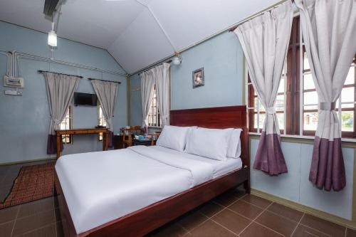 een slaapkamer met een bed met witte lakens en ramen bij OYO 89873 Nurbayu Chalet in Kuantan