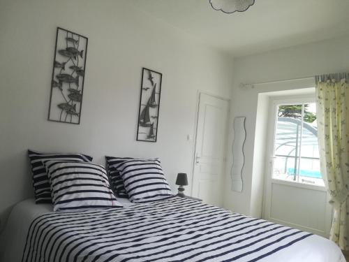 a bedroom with a bed with striped pillows and a window at Gite LES BALISES- BABORD-Maisons de bord de mer avec spa -SAINT GILLES CROIX DE VIE - 27 Avenue NOTRE DAME in Saint-Gilles-Croix-de-Vie