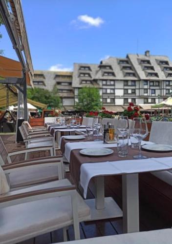 a row of white tables and chairs with a building at Megi apartman - Konaci Maglic in Kopaonik