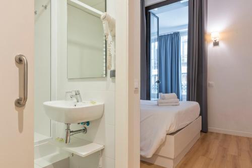 y baño con cama, lavabo y espejo. en Hostalin Barcelona Gran Via, en Barcelona