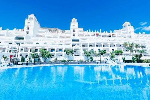 a large white building with a swimming pool in front of it at Hollywood Mirage - Excel Hotels & Resorts in Los Cristianos