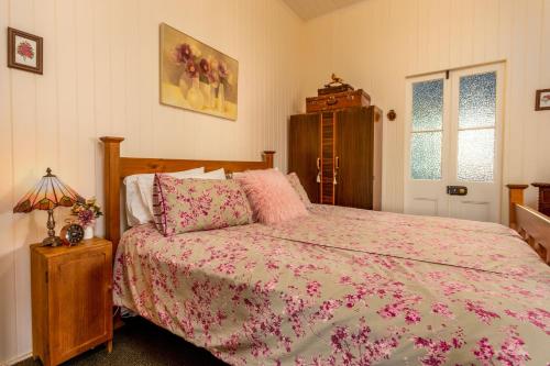 a bedroom with a bed with a pink comforter at Dillons Cottage in Stanthorpe