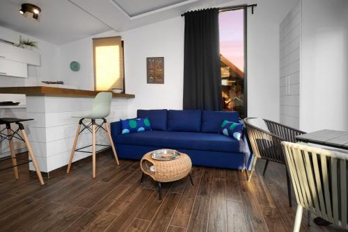 a living room with a blue couch and a kitchen at Beach House Belgrade in Belgrade