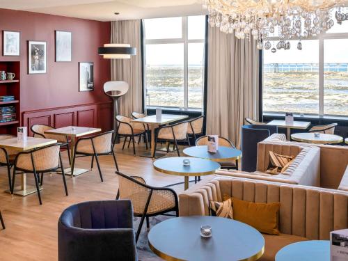 a restaurant with tables and chairs and a couch at Hotel Mercure Roscoff Bord De Mer in Roscoff