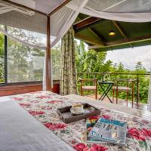 a bedroom with a bed with a table and a balcony at The Source At Sula in Nashik