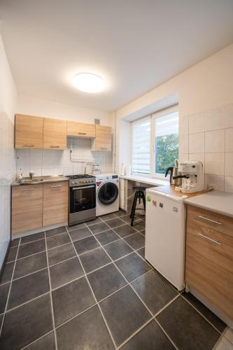 a kitchen with wooden cabinets and a tile floor at Wonderful Apartment in the City Center in Šiauliai