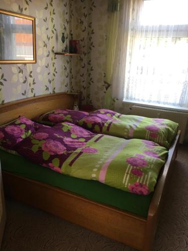 a bed with a green and pink comforter and a window at Ferienwohnung bunte Stadt an der Elde in Grabow