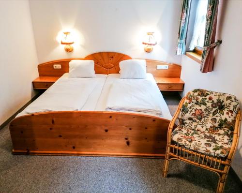 a bedroom with a wooden bed and a chair at Haus am Römerbad in Bad Kleinkirchheim