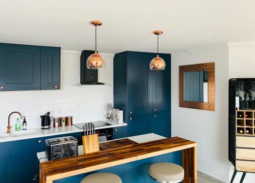 a kitchen with blue cabinets and a counter with stools at The Lookout in Swanage