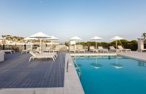a swimming pool with lounge chairs and umbrellas at Jo An Palace in Rethymno Town