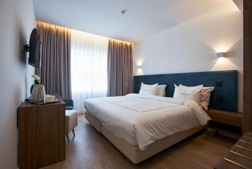 a bedroom with a large bed and a television at Hotel Moutados in Vila Nova de Famalicão