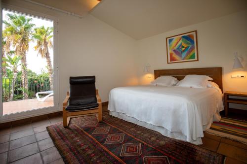 a bedroom with a bed and a chair and a window at Tancat de Codorniu in Les Cases d'Alcanar