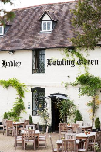a white building with tables and chairs in front of it at Hadley Bowling Green Inn in Droitwich