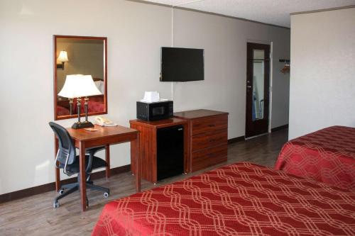 a hotel room with a desk and a bed and a television at Econo Lodge Salina Scenic Route 89 & I-70 in Salina