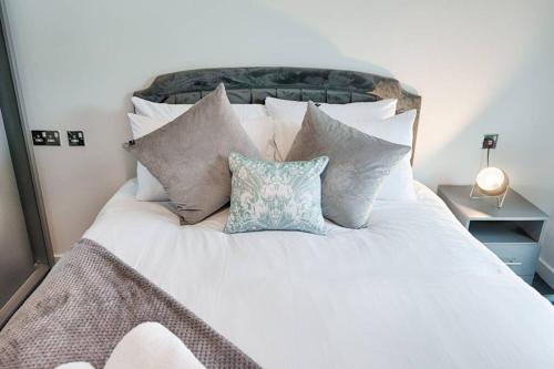 Una cama blanca con un montón de almohadas. en Stay at Neptune with Parking Space - TV in every Bedroom!, en Swansea