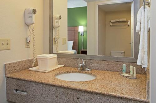 a bathroom counter with a sink and a mirror at Quality Suites Lake Wright Norfolk Airport in Virginia Beach