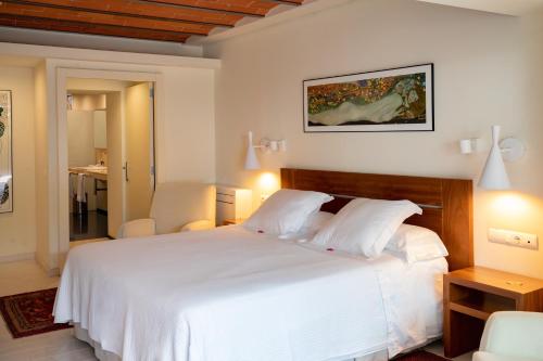 a bedroom with a large white bed with two chairs at Tancat de Codorniu in Les Cases d'Alcanar