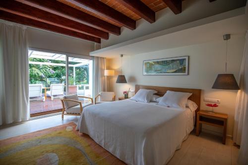 a bedroom with a white bed and a large window at Hotel Tancat de Codorniu in Les Cases d'Alcanar