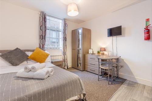 a bedroom with a bed and a desk and a television at Guest Homes - The Foregate in Worcester