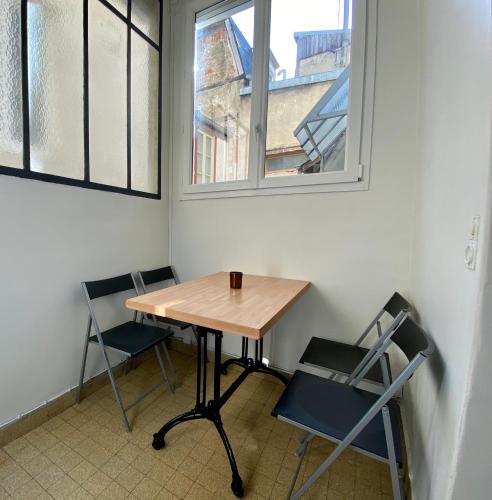 une table et des chaises dans une pièce avec deux fenêtres dans l'établissement Studio ChaBada - 1min de la plage & des commerces, à Trouville-sur-Mer