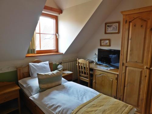 a small bedroom with a bed and a television at Berki Vendéglő és Hotel in Körmend