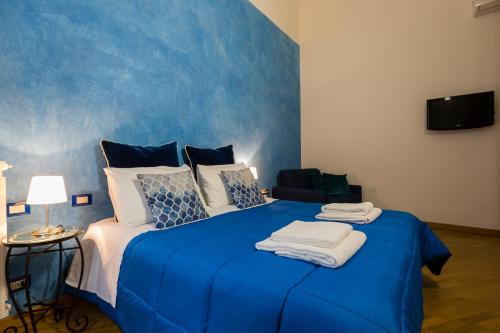 una camera da letto con un letto blu e asciugamani di La Locandiera B&B a Firenze
