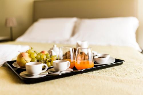 a tray of fruit and coffee on a bed at Domus Hyblaea Resort in Palazzolo Acreide