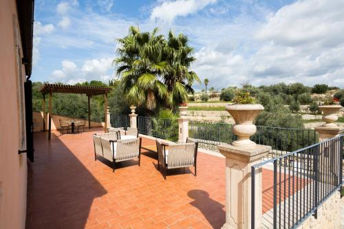 a patio with chairs and tables and a fence at Domus Hyblaea Resort in Palazzolo Acreide