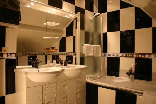 uma casa de banho com 2 lavatórios, uma banheira e um espelho. em Hotel Le Relais de Pommard em Francorchamps