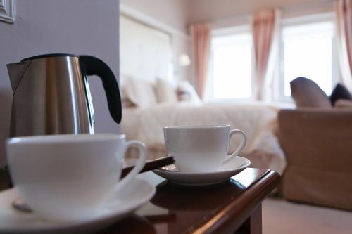 eine Kaffeekanne und zwei Tassen auf dem Tisch in der Unterkunft Dún Ard in Dungarvan