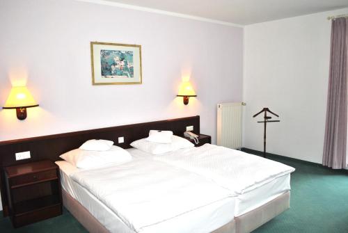 a bedroom with a large white bed with two lamps at Heidehotel Lubast in Lubast