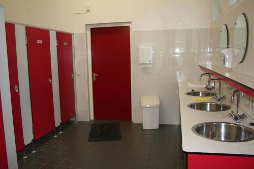 een badkamer met 2 wastafels en 2 rode deuren bij Camping 't Bosch in Zelhem