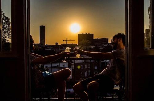 two people sitting on a balcony with the sunset at Hostel Roots in Tilburg