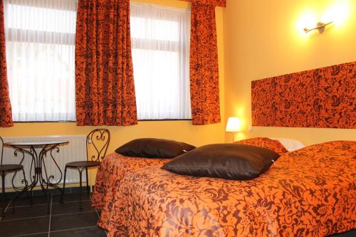 a bedroom with a bed and a table and windows at Hotel Le Relais de Pommard in Francorchamps