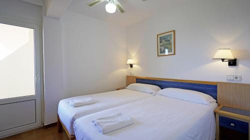 埃斯普霍斯的住宿－Apartamentos Portu Saler，一间卧室设有两张带白色床单的床和窗户。