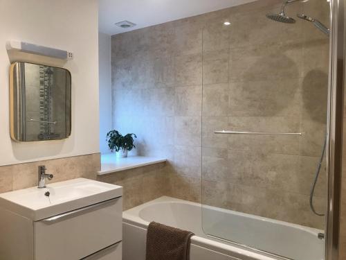 a bathroom with a shower and a tub and a sink at Towennan - four bedroomed apartment in quiet seaside village. in Gwithian