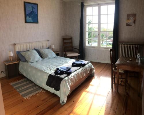 um quarto com uma cama, uma secretária e uma janela em La Maison Blanche em Saint-Jean-dʼAngély